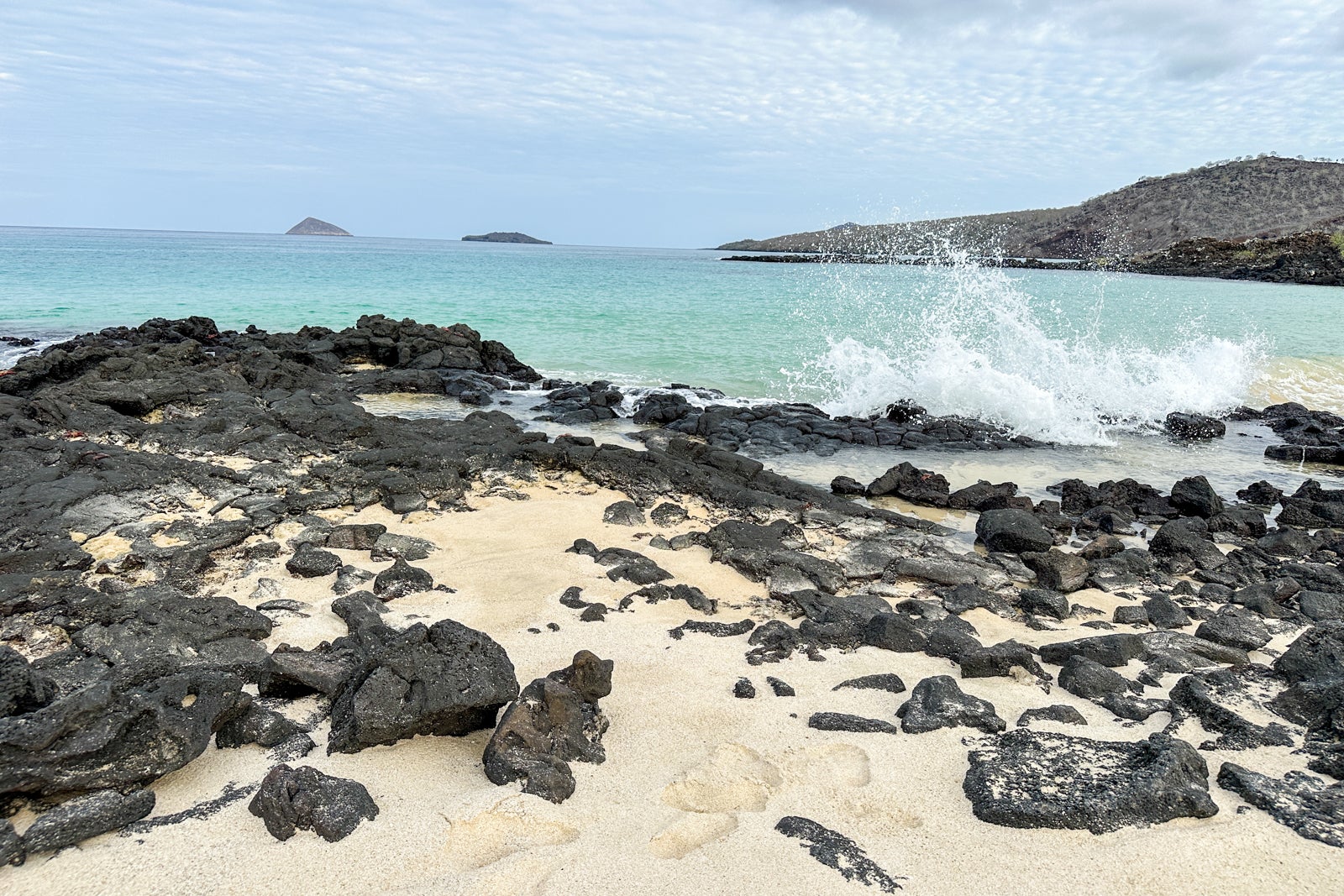 waves crash over black rocks