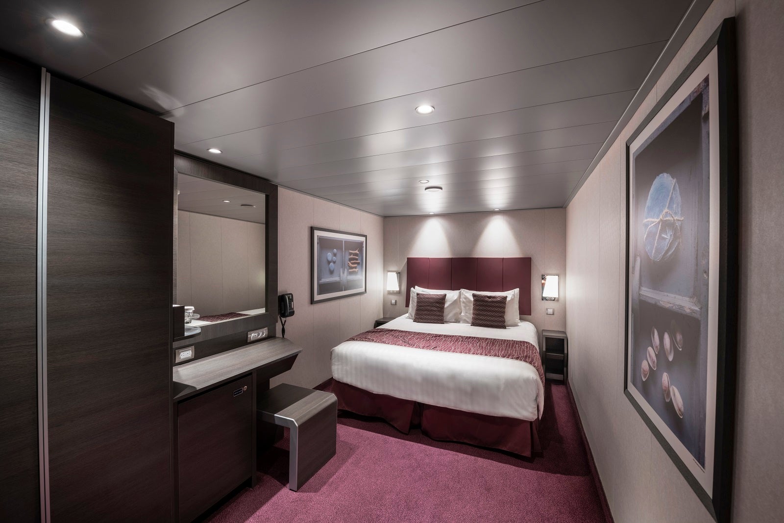 An inside cruise cabin with a bed, desk and mirror