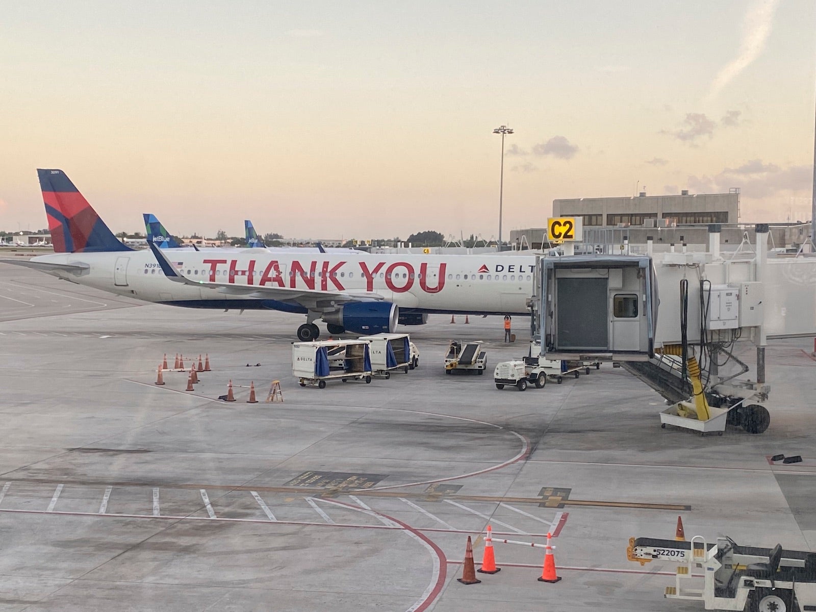 Delta airplane with Thank You message on side, being loaded with baggage before taking off, West Palm Beach Gardens Airport, Florida