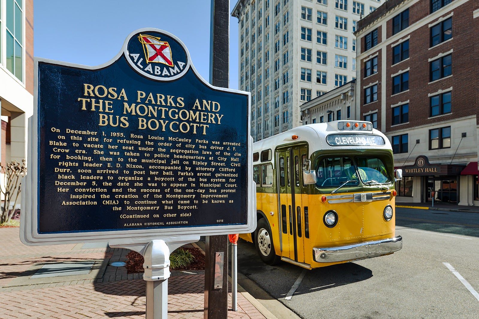 a yellow bus sits behind a historical marker labeled Rosa Parks and the Montgomery Bus Boycott