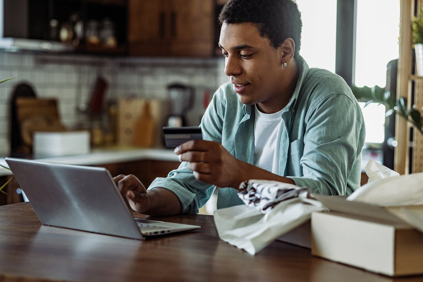 a young man in a kitchen using a laptop