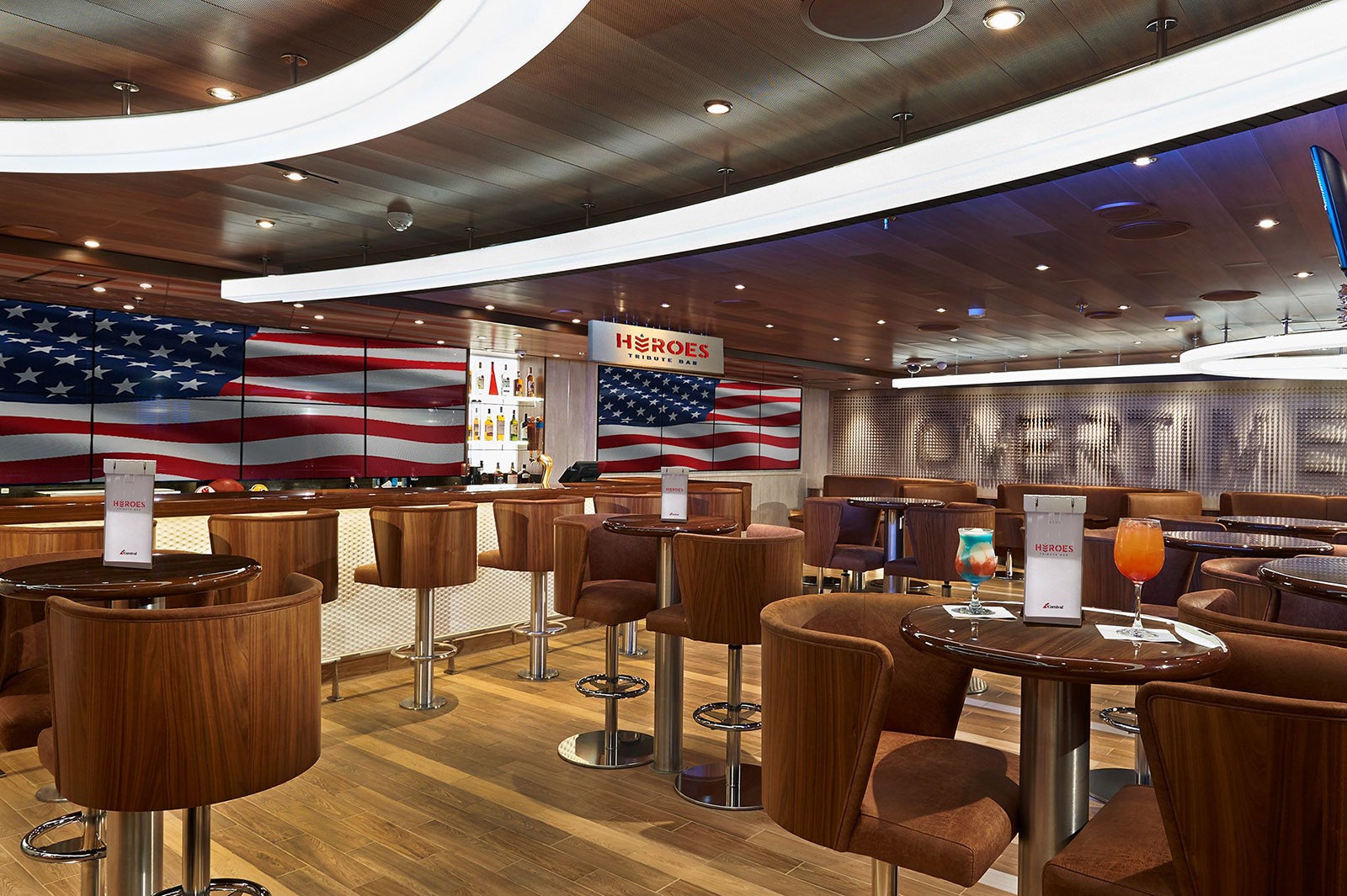 Cruise ship bar with brown chairs and tables and TV showing US flag