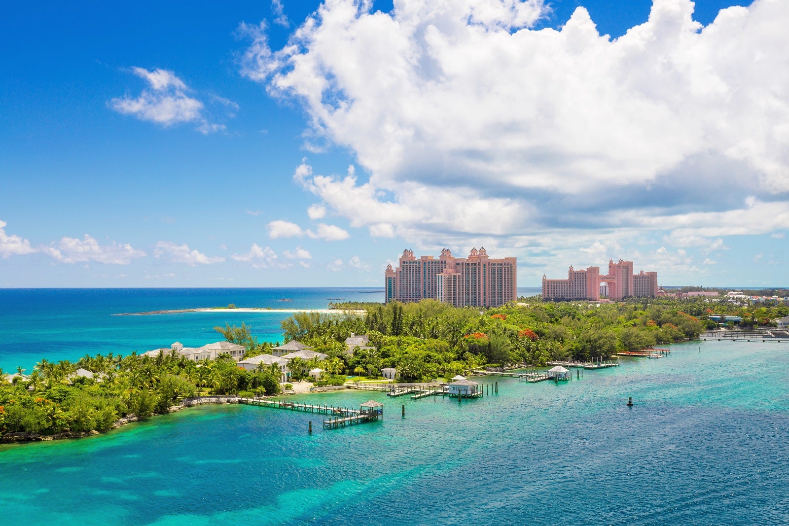 An aerial view of Atlantis resort on Paradise Island in the Bahamas set in green vegetation in teal water with a blue sky with white clouds overhead