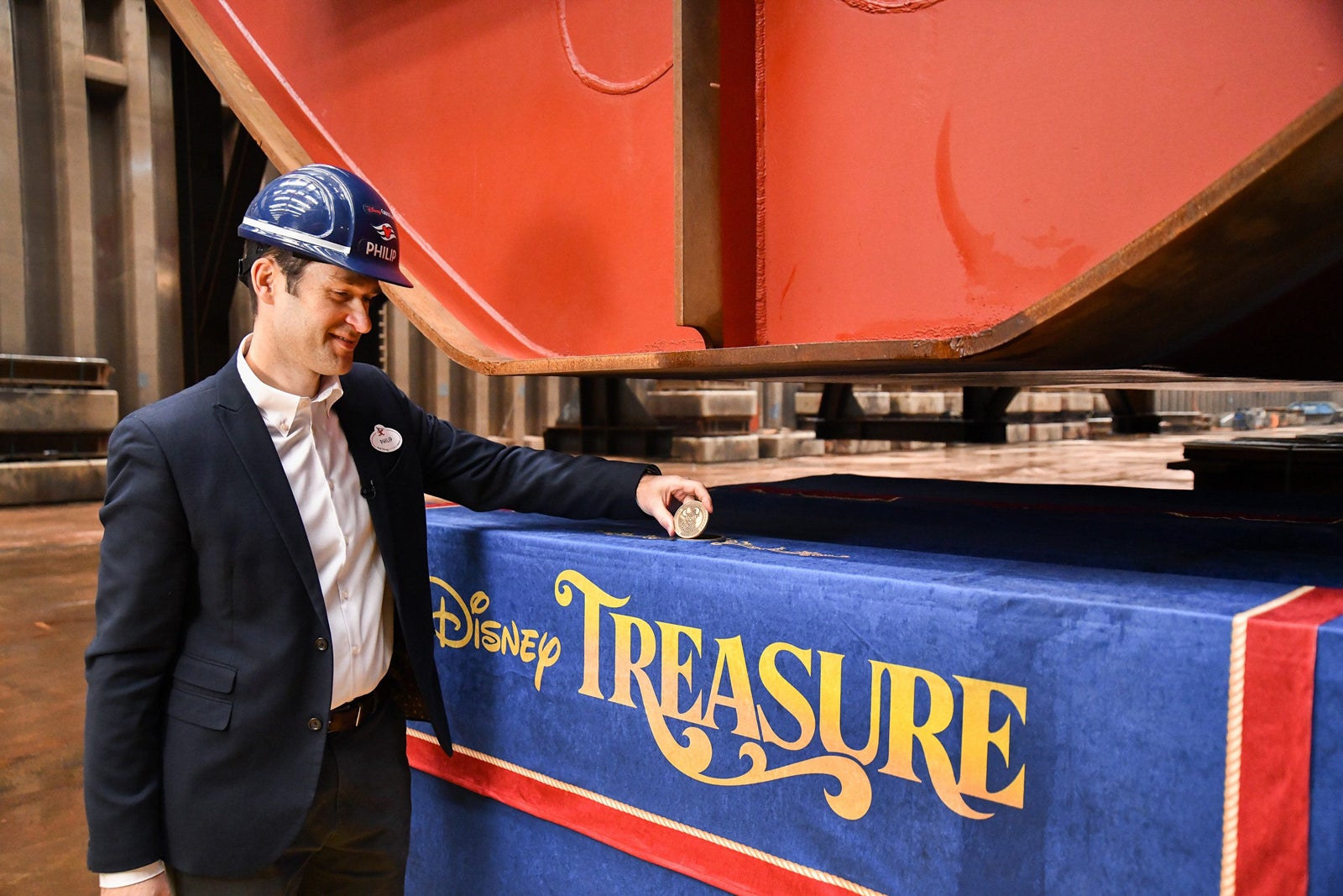 Man in hard hat places special coin in Disney Treasure keel laying ceremony