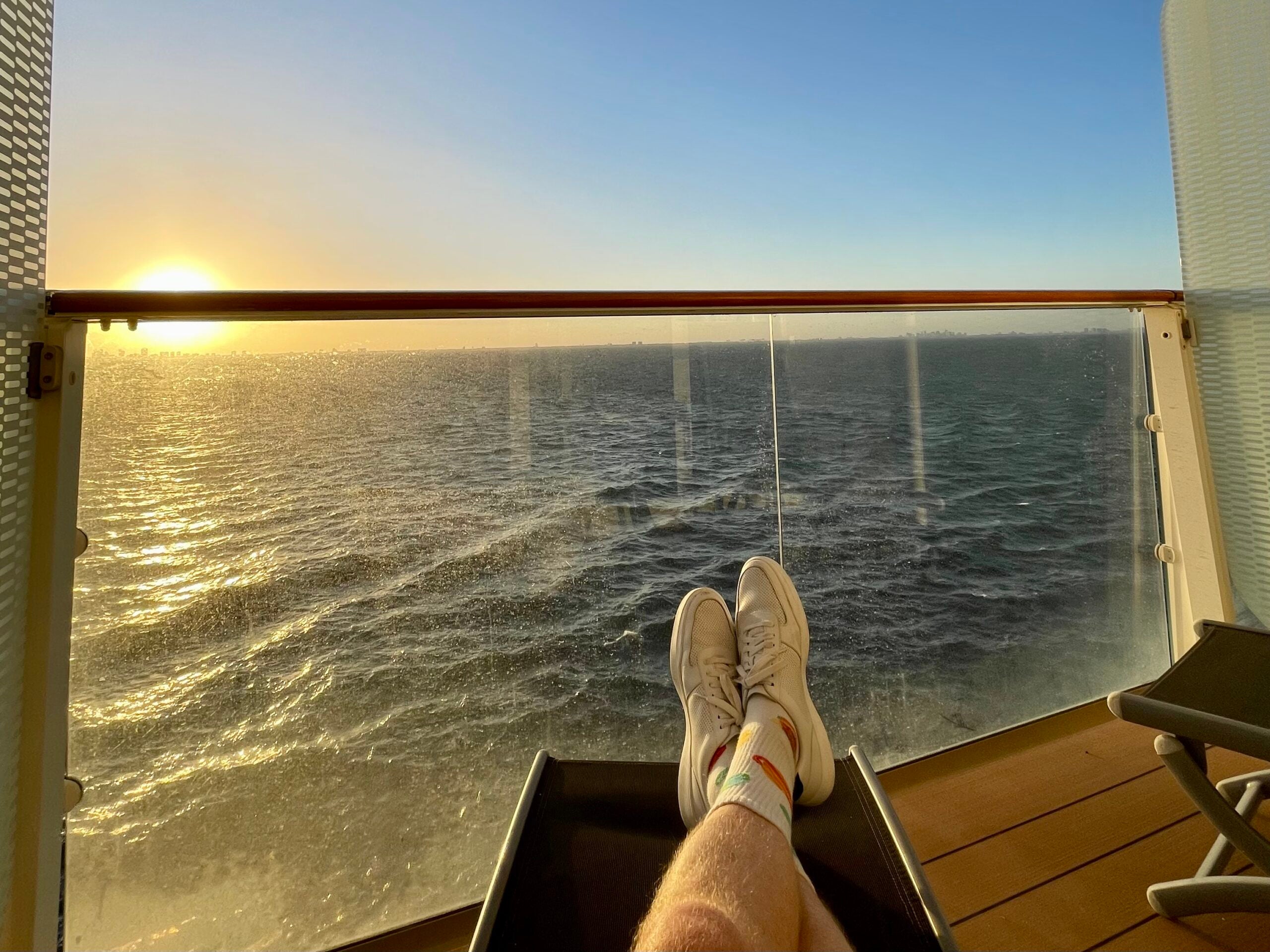 Feet on deck chair on cruise ship balcony