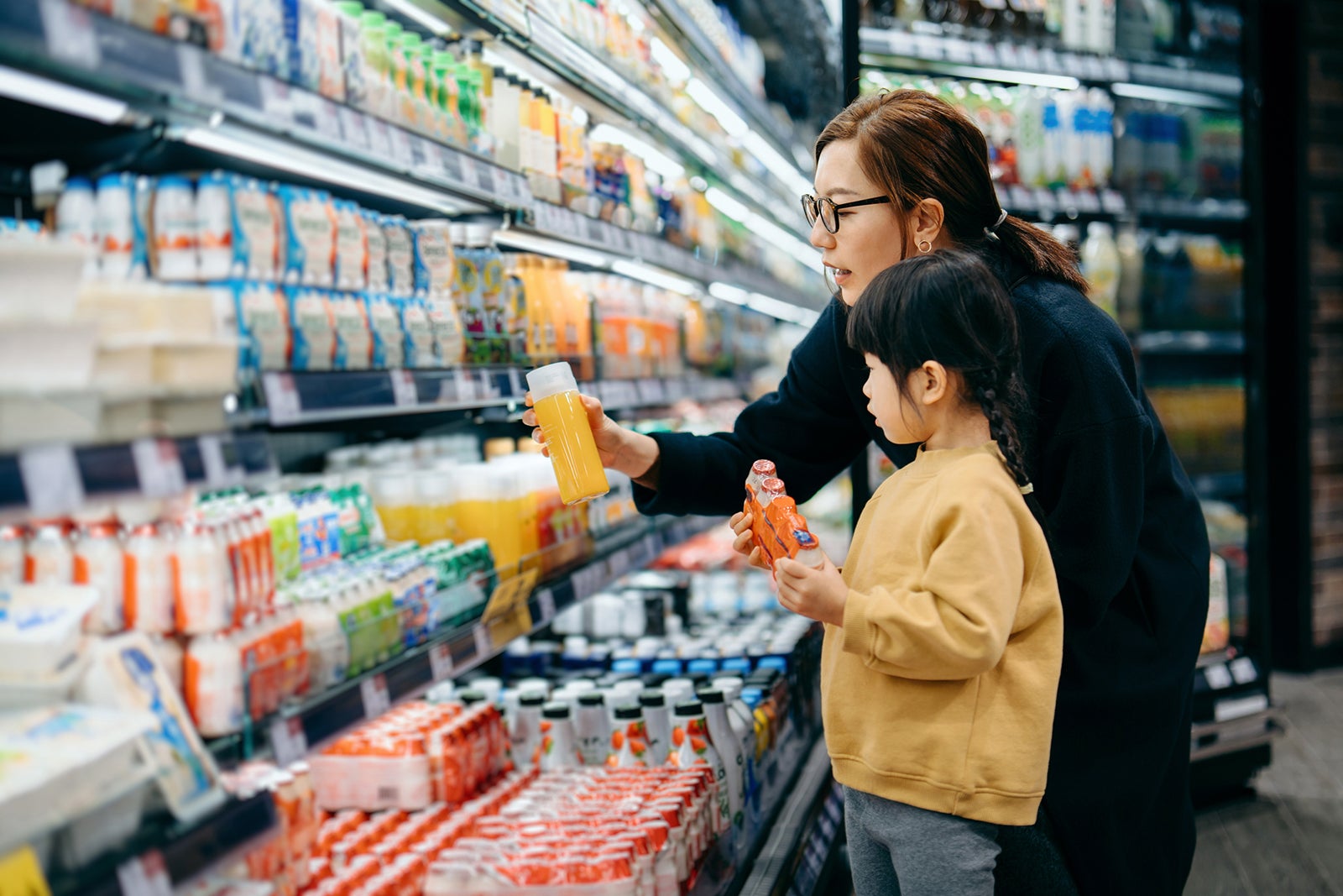 woman and child looking at juice bottles in a grocery store