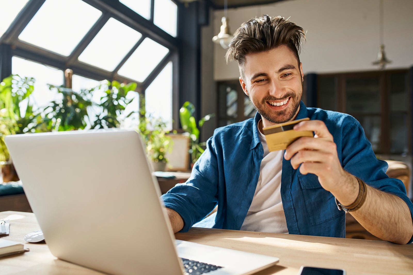 Young businessman paying through credit card while using laptop in office