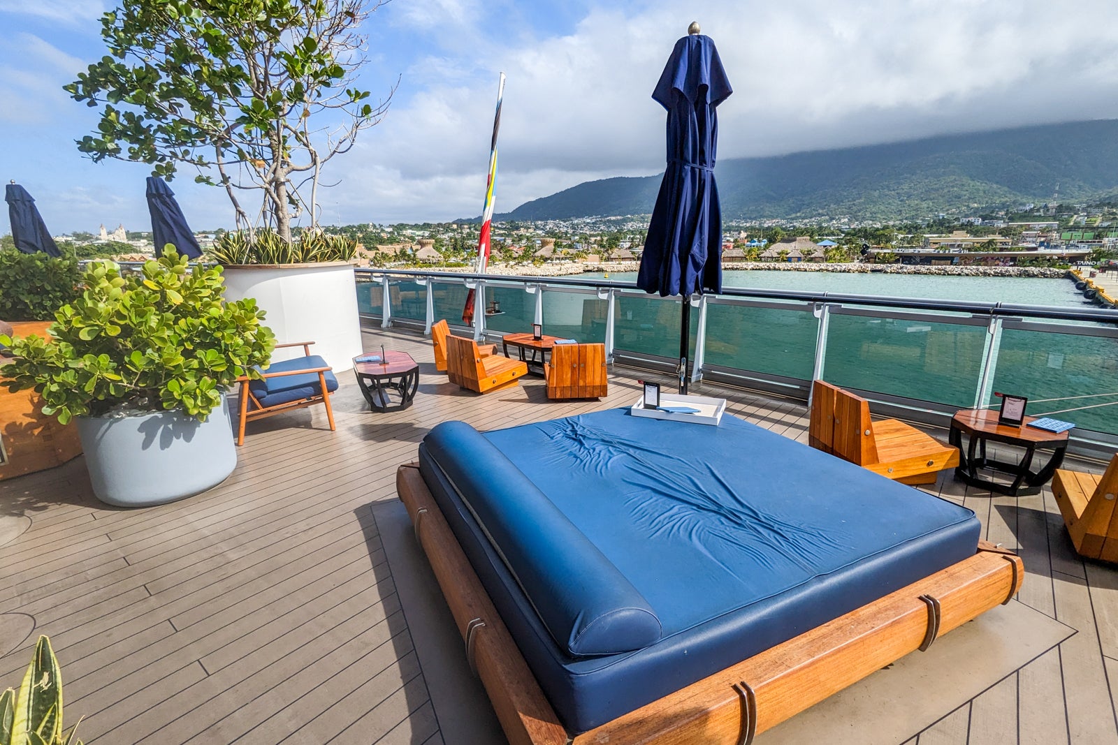 Outdoor cruise ship lounge with blue day beds and wooden seating areas