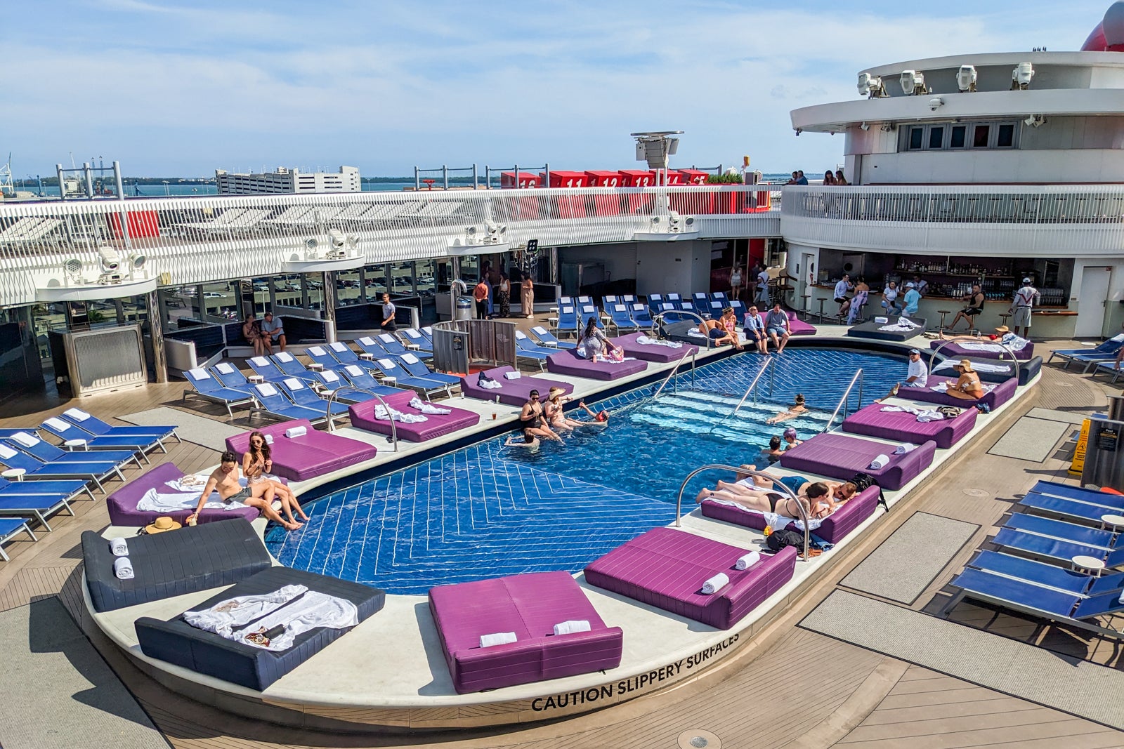 Pool surrounded by purple day beds on cruise ship