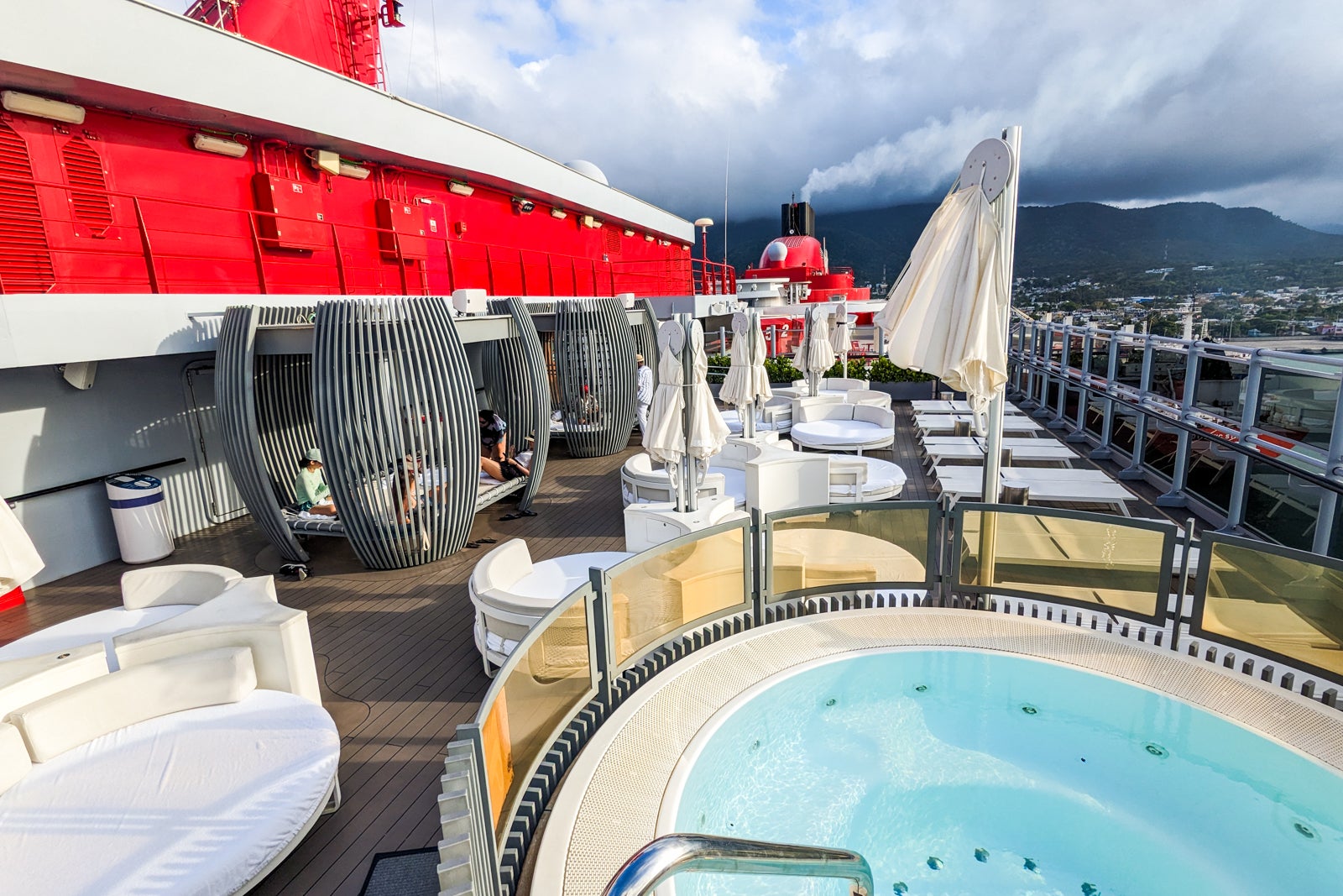 VIP cruise ship pool deck with hot tubs and white day beds.