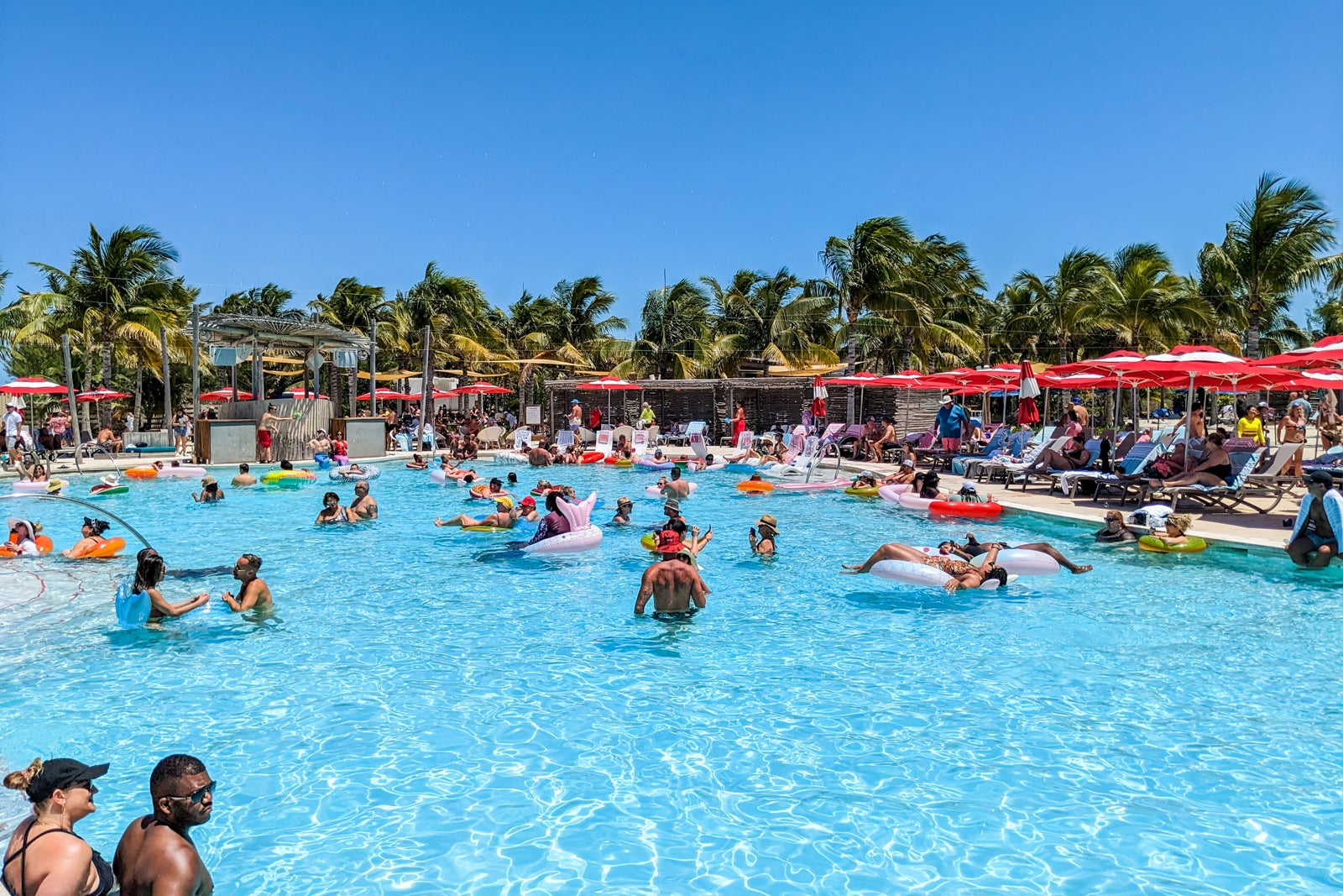 Pool with floats, surrounded by red umbrellas