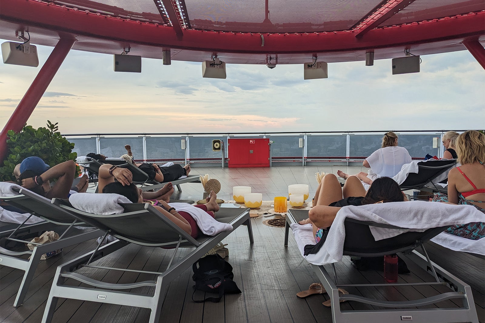 Women lying on lounge chairs with setup of singing bowls