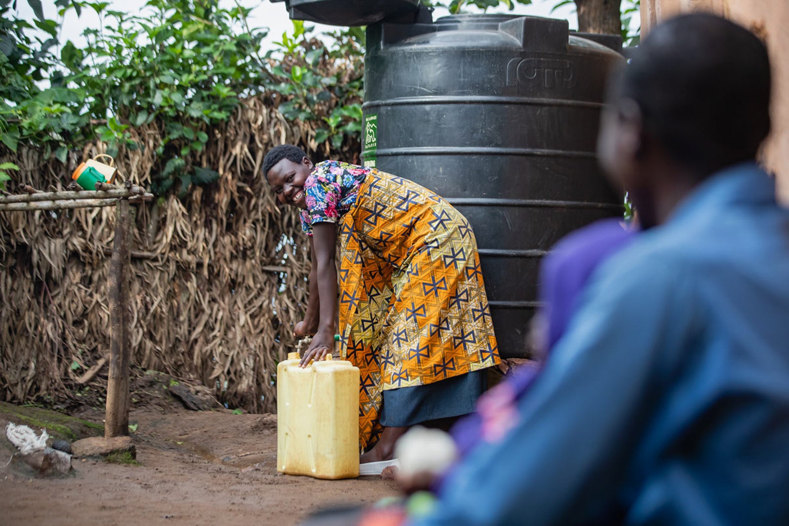 A Rwandan woman uses one of the water tanks donated to her village by Volcanoes Safaris.