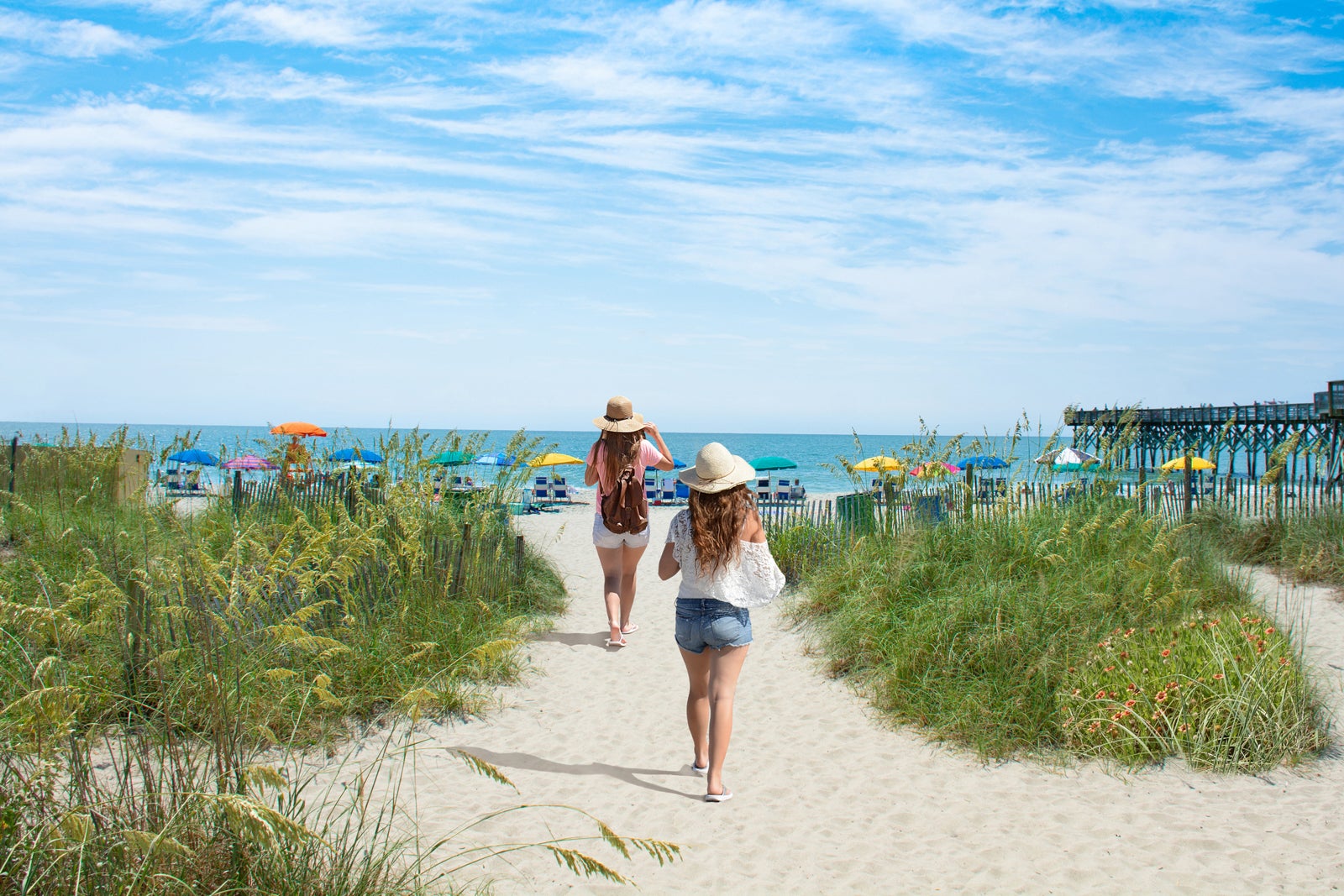 Girls waking on the beach. Footpath on sand dunes and ocean in the background. Myrtle Beach, South Carolina, USA