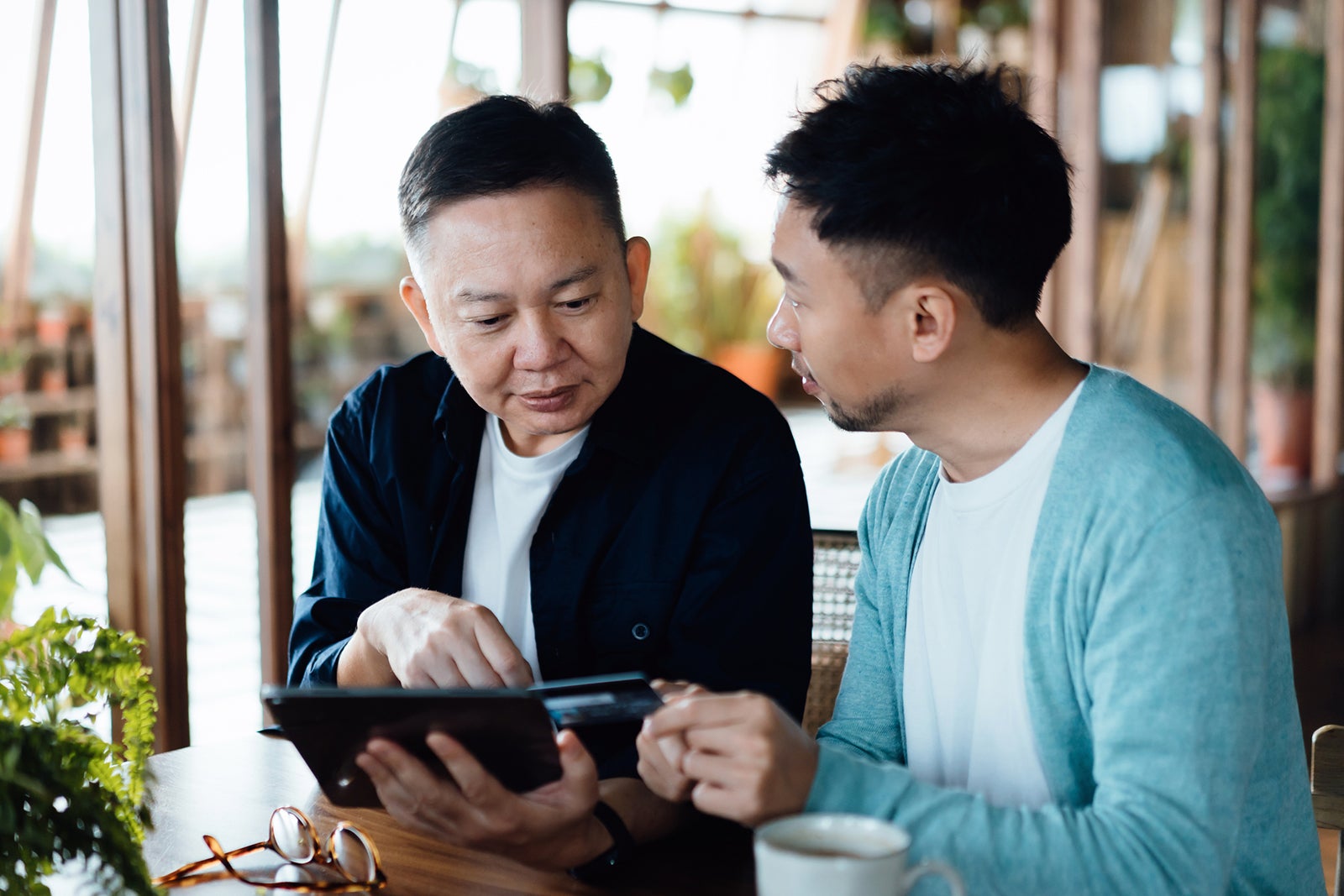 Father and son use tablet and credit card at home