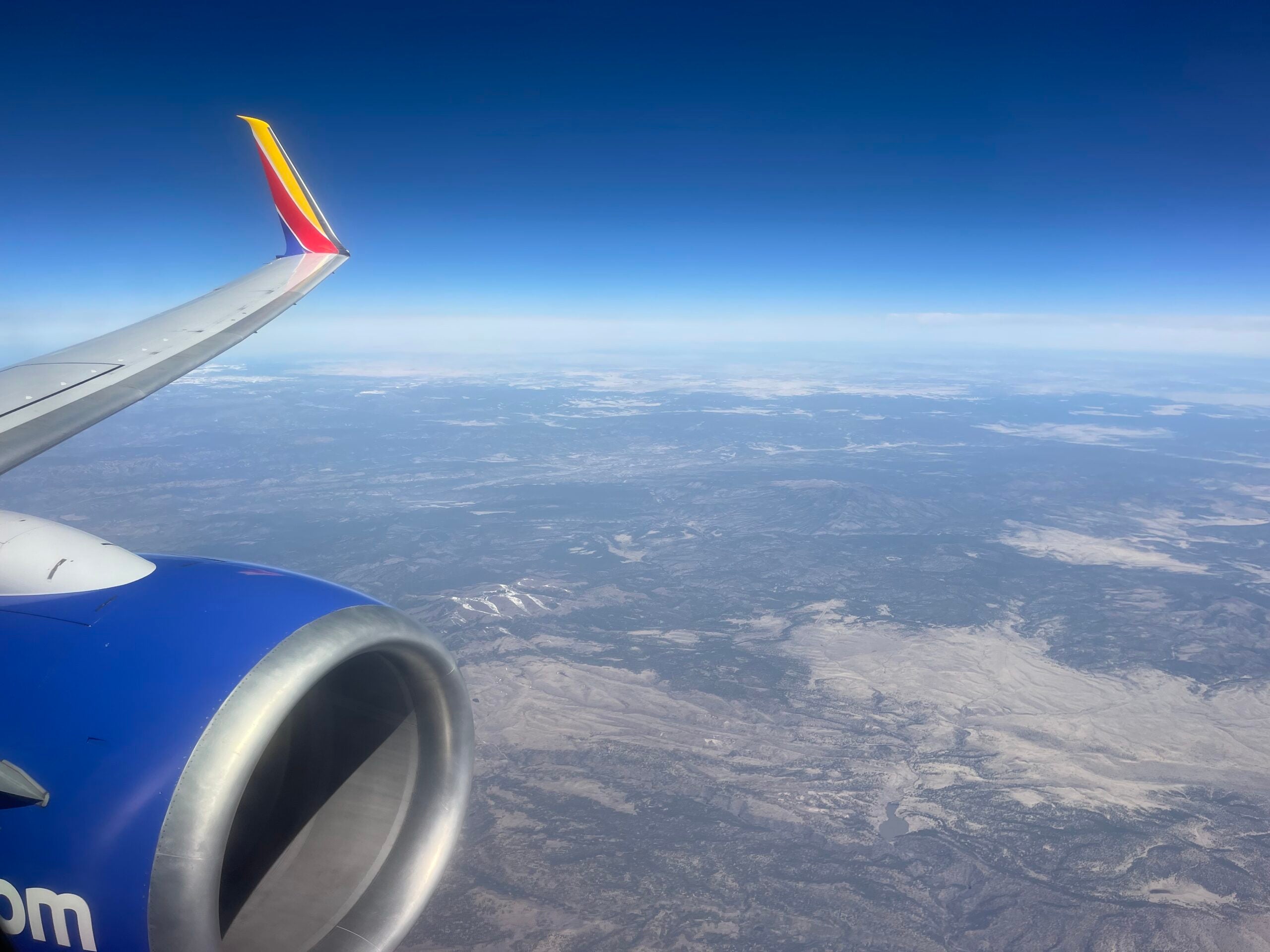 Looking out the window of a Southwest Airlines plane, with parts of the wing and engine seen above the landscape