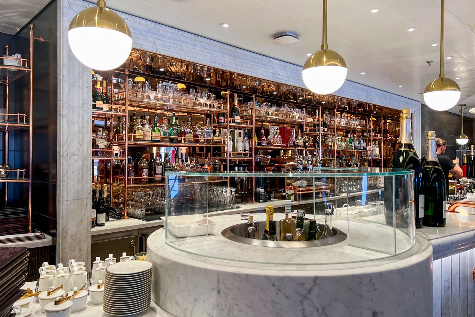 A rounded bar with a wall full of alcohol bottles behind it