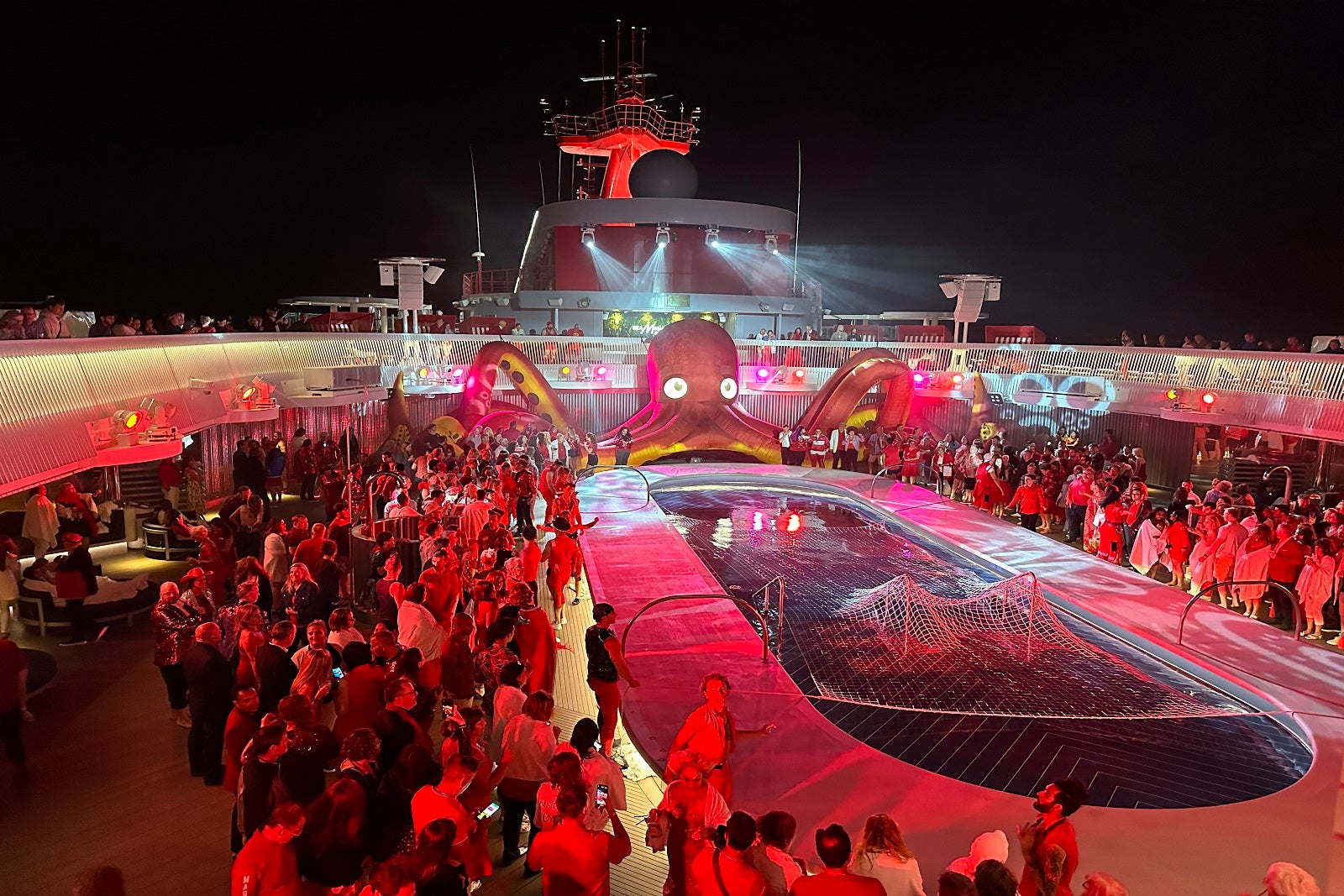 Passengers crowd around the pool for a rave-style Scarlet Night party on Virgin Voyages' Resilient Lady.