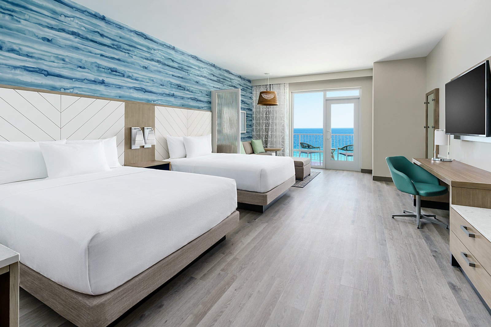 A hotel room decorated in shades of blue and white with two beds and a view of the ocean.
