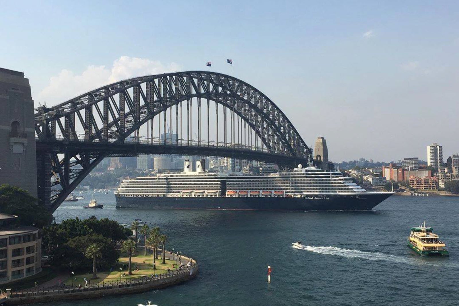 A cruise ship sails under a bridge.