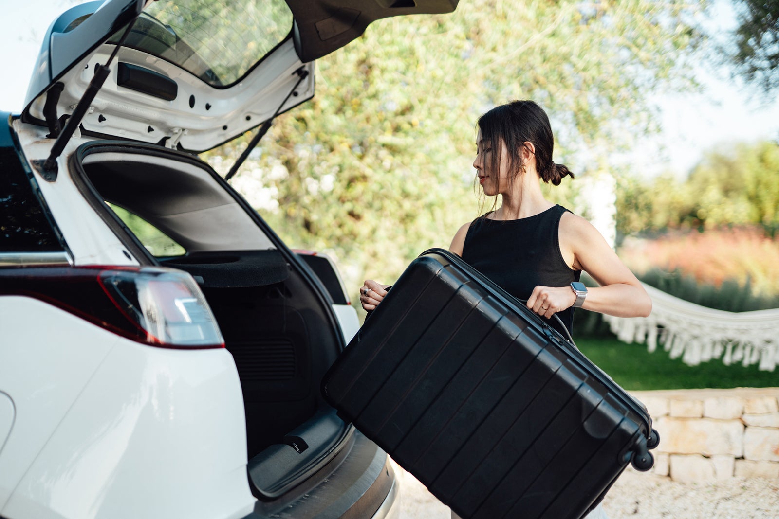 woman loading luggage into car, getting ready for a road trip