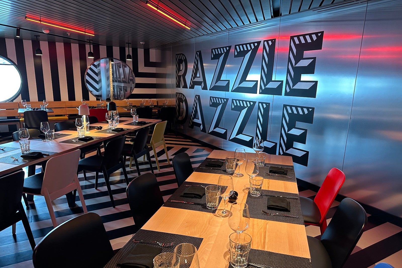 A restaurant with long tables, striped decor and the words "Razzle Dazzle" on the wall