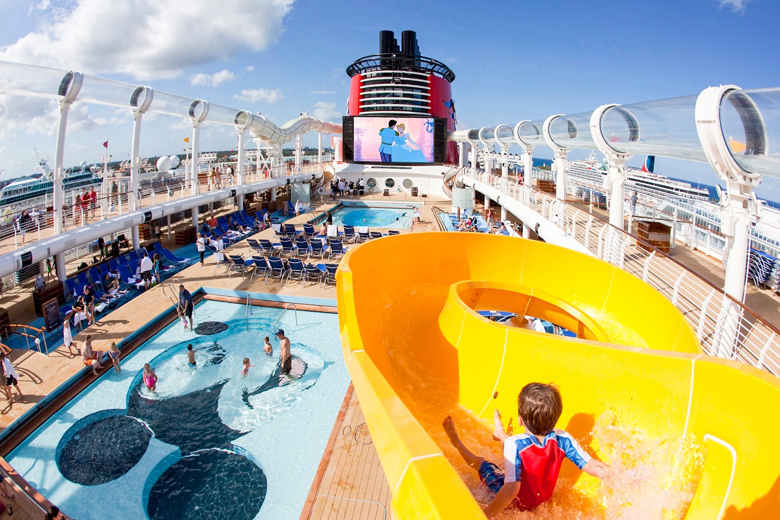 A child slides down a yellow water slide on a cruise ship