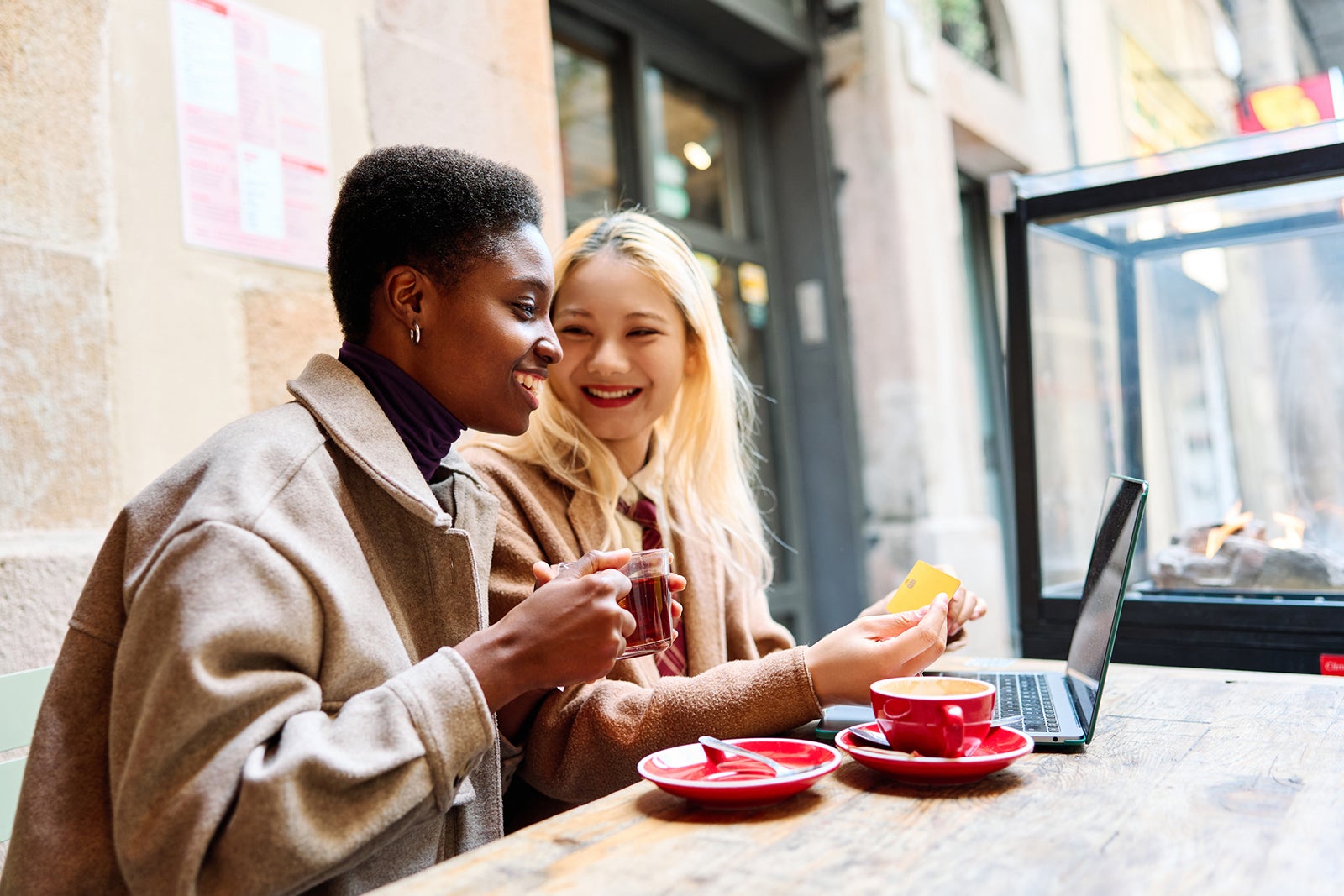 Multiethnic tourists shopping online with credit card sitting in a cafeteria