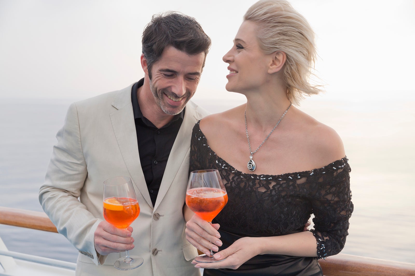 Dressed-up couple with cocktails on deck of cruise ship