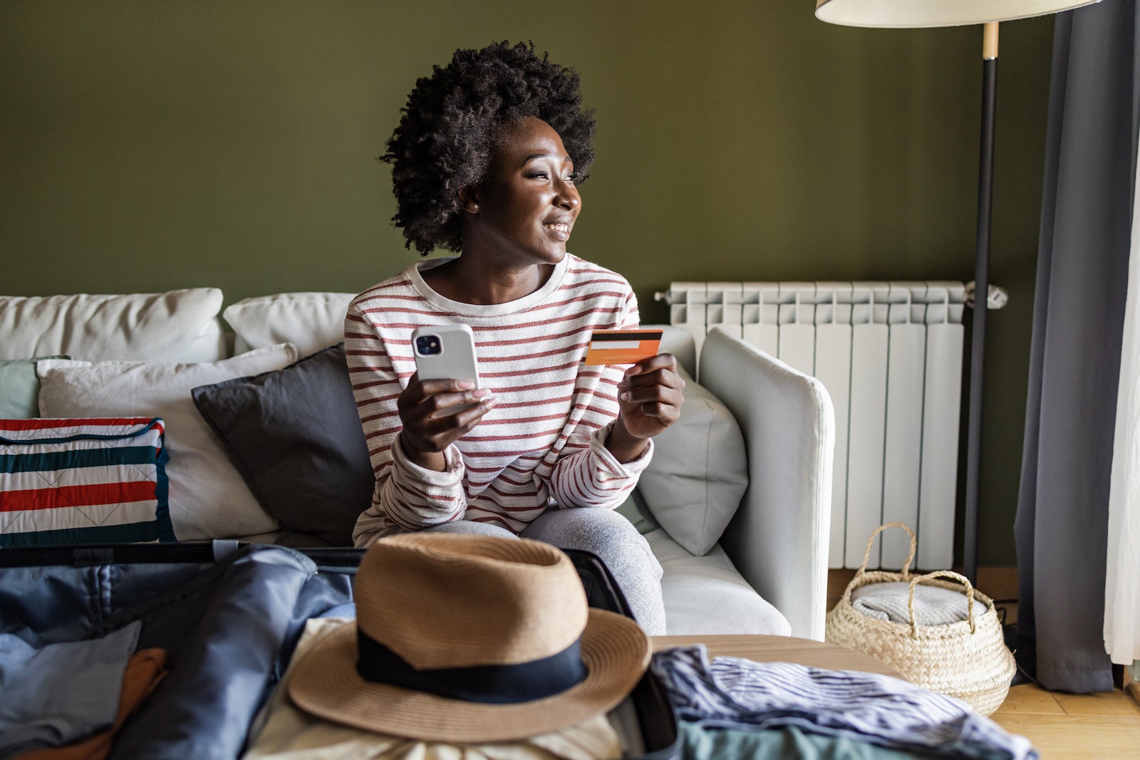 woman holding a phone and a credit card looking out a window