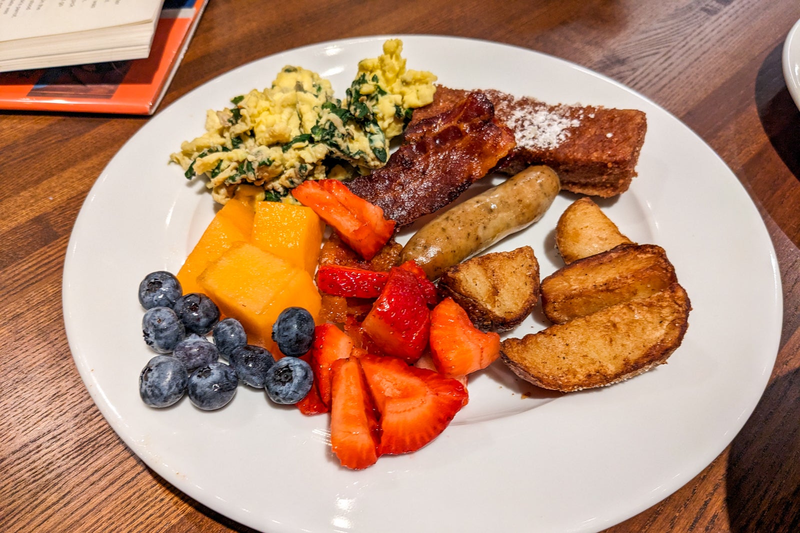 Plate of eggs, French toast, sausage, fruit and breakfast potatoes
