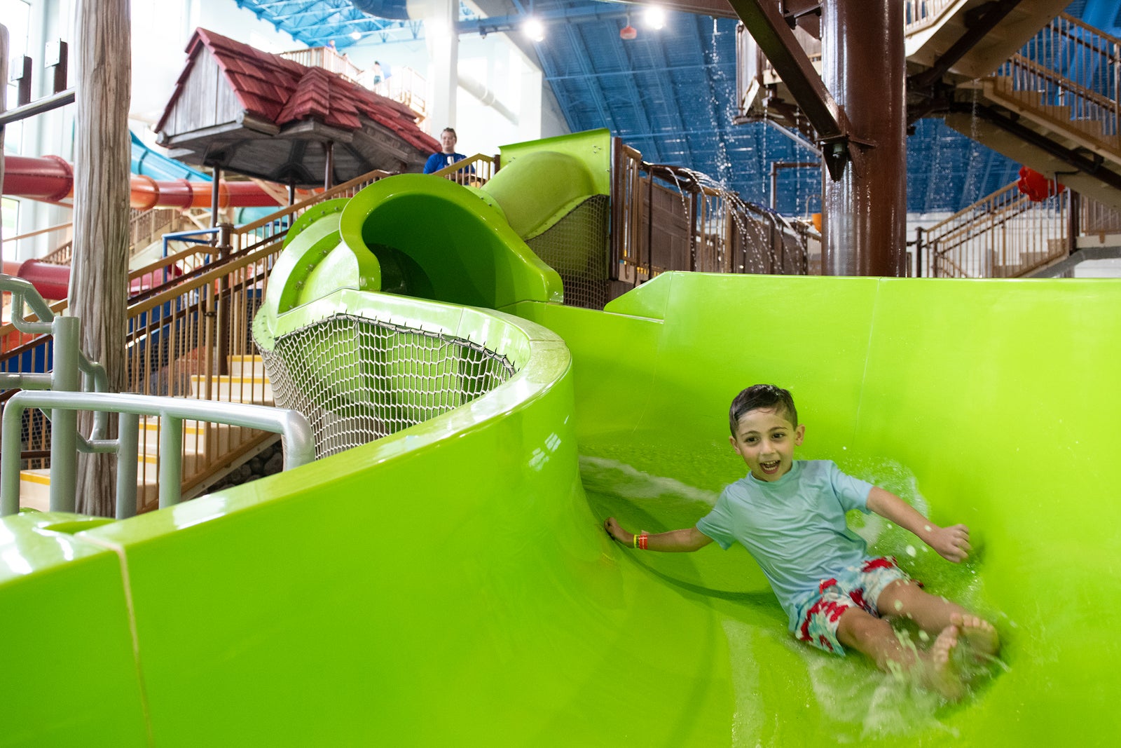Boy sliding down green body slide at Great Wolf Lodge Maryland