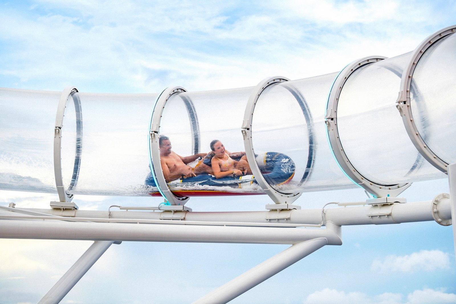 Two cruise passengers on double raft going through clear tube slide