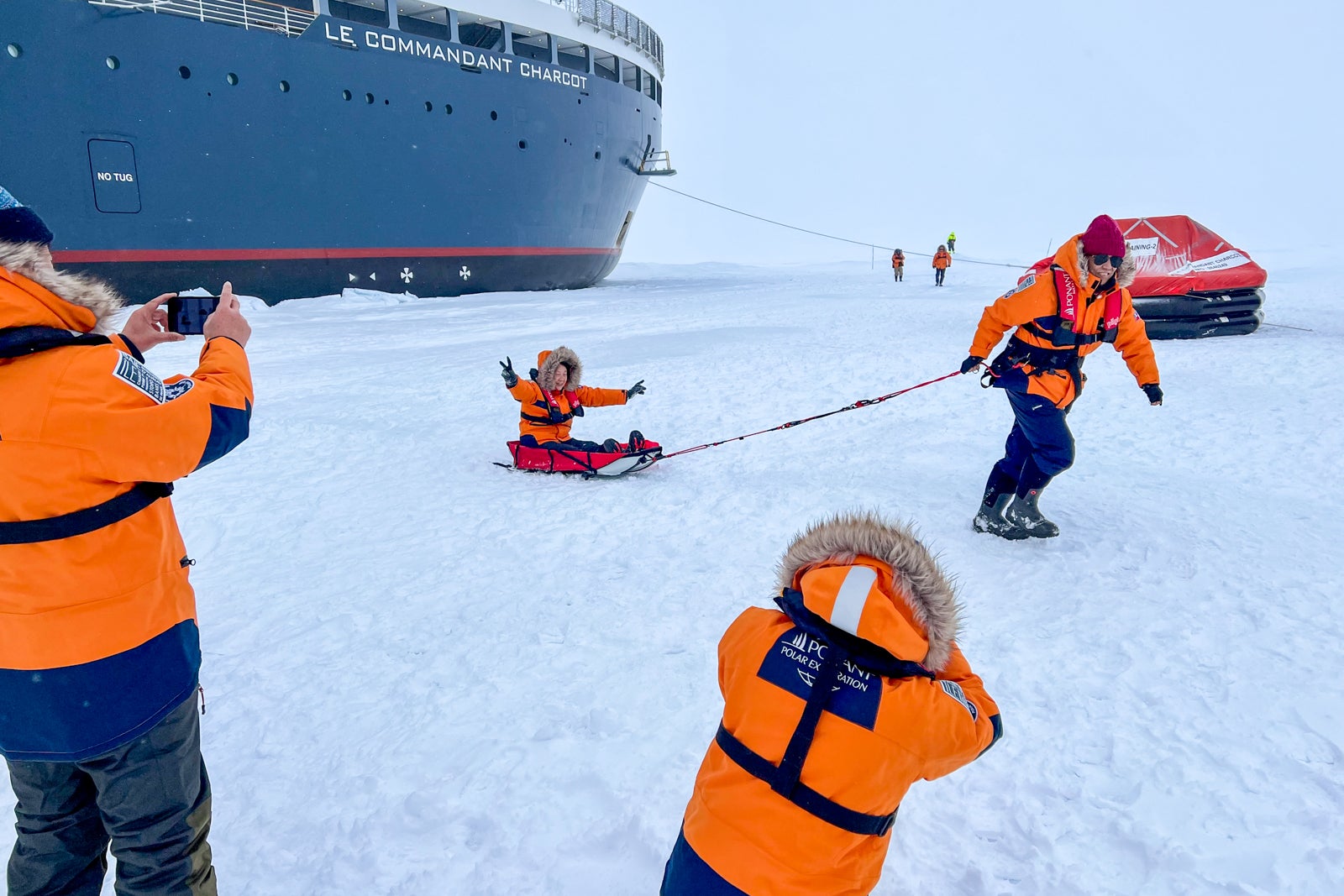 People pulling each other in sleds by cruise ship at North Pole