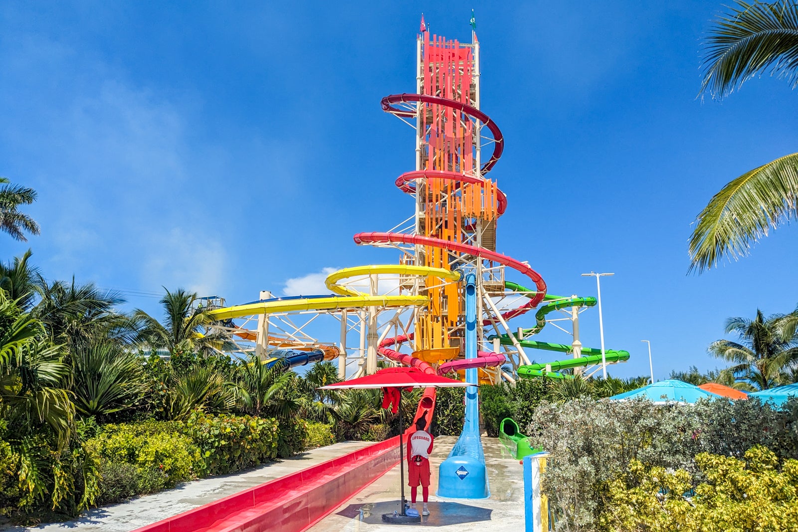 Multicolored water slide tower set amid blue sky and palm trees