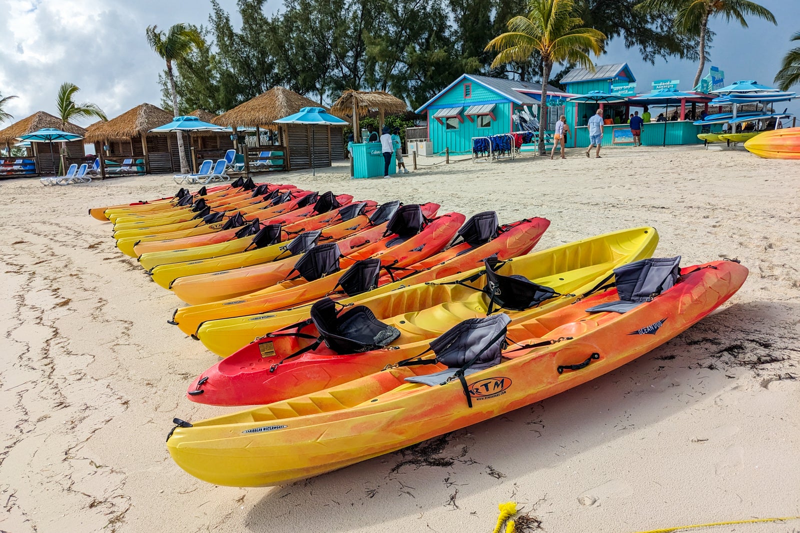Line of yellow and orange kayaks on the beach