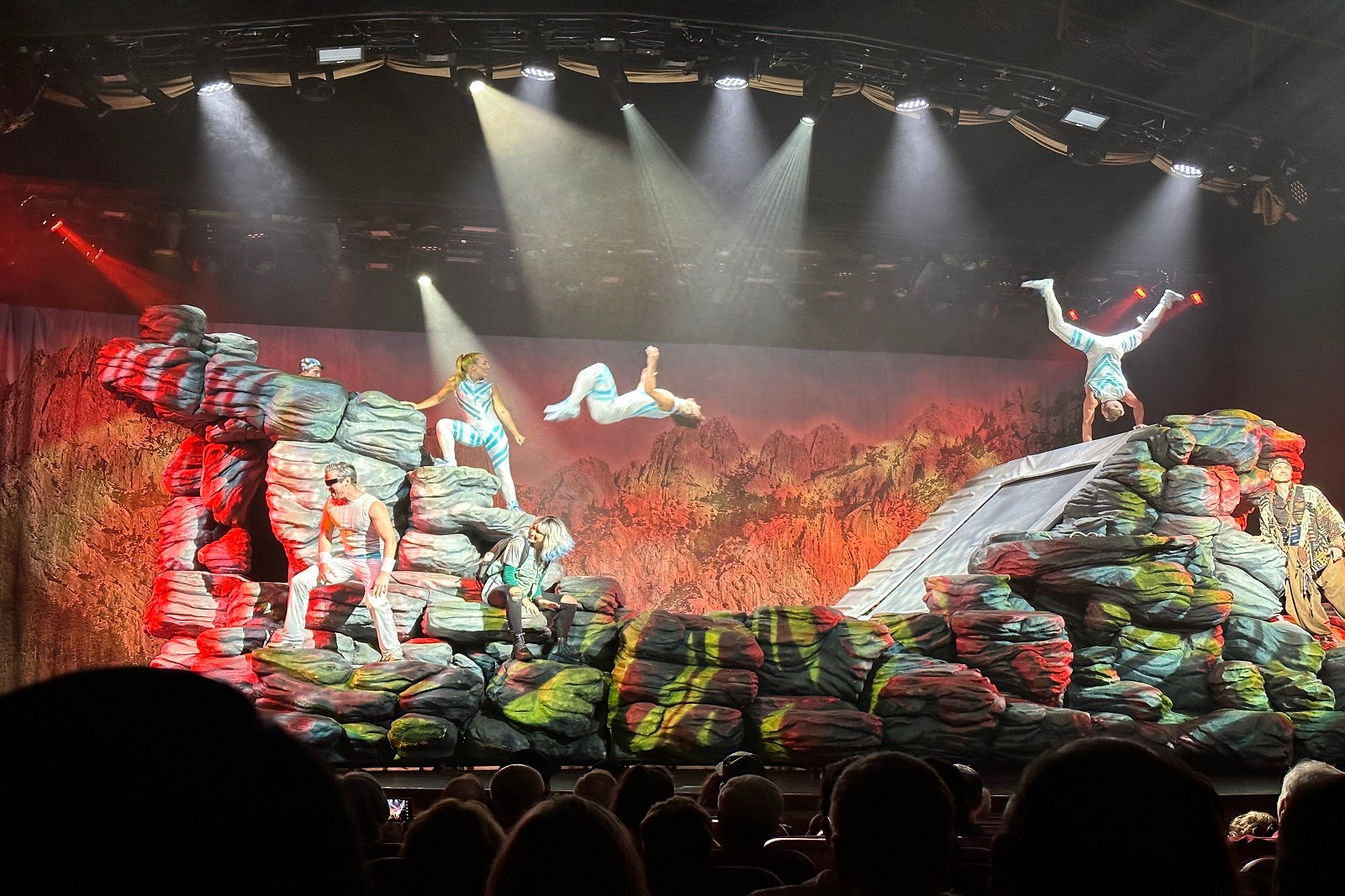 Acrobats flipping between faux rocks during a performance in a cruise ship theater