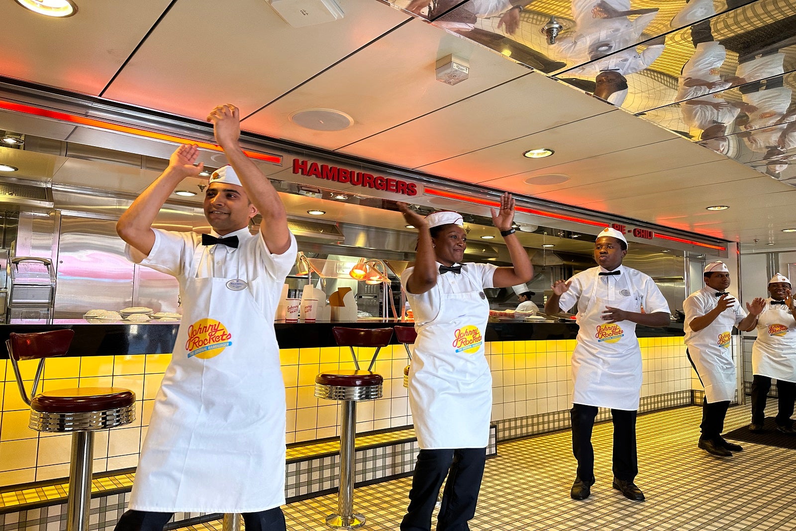 Five waiters singing and dancing at a cruise ship burger restaurant