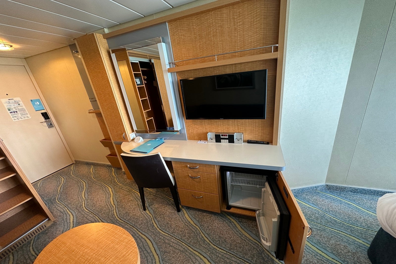 The desk/vanity area, along with a minifridge and TV in a cruise ship cabin