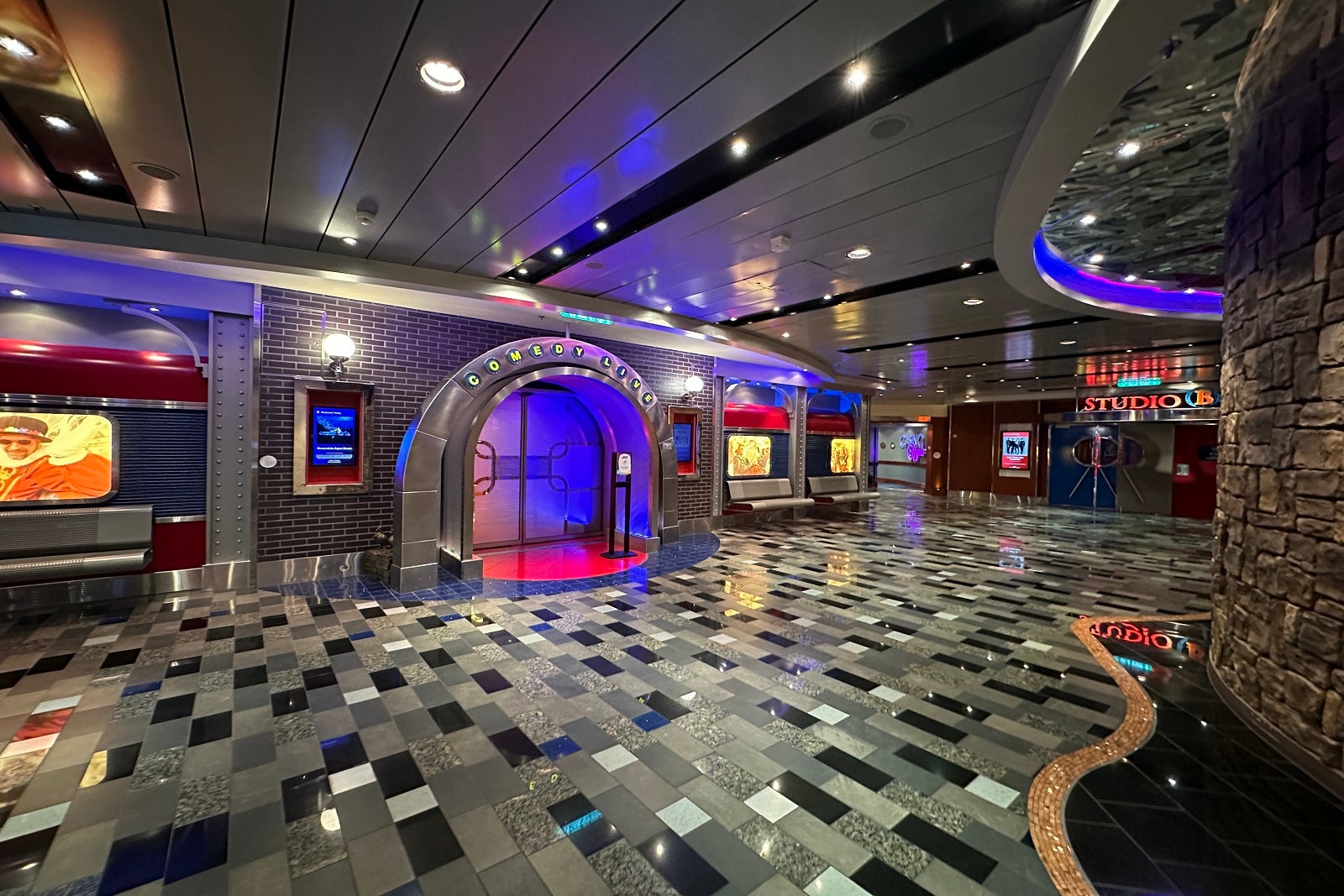 A tiled walkway with entrances to multiple entertainment venues on a cruise ship