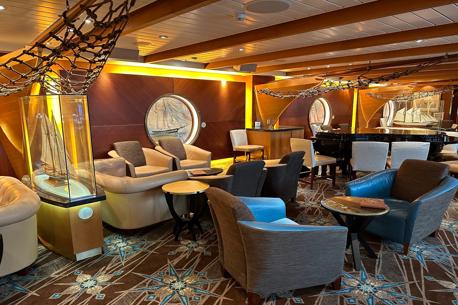 A nautically themed cruise ship bar with porthole windows, fishing nets and ship memorabilia as decor