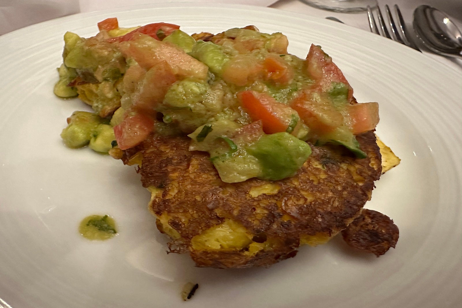 A corn cake topped with salsa on a white plate