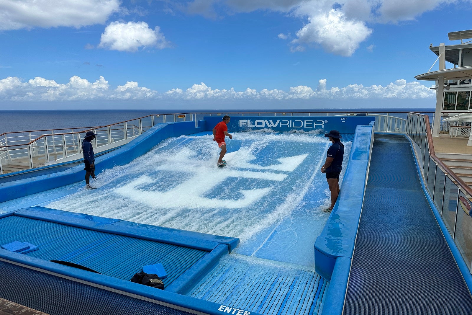 A person surfing on a surf simulator on a cruise ship withe Royal Caribbean logo on it