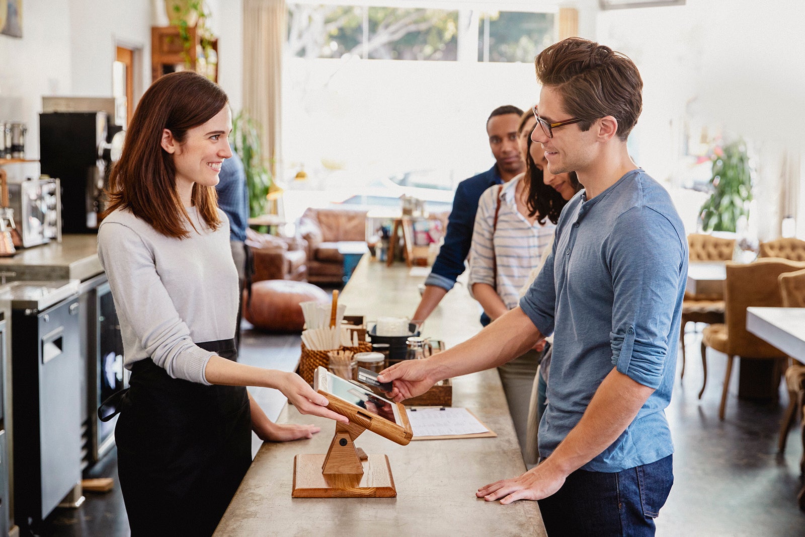 Customer at the front of the queue paying in a coffee shop