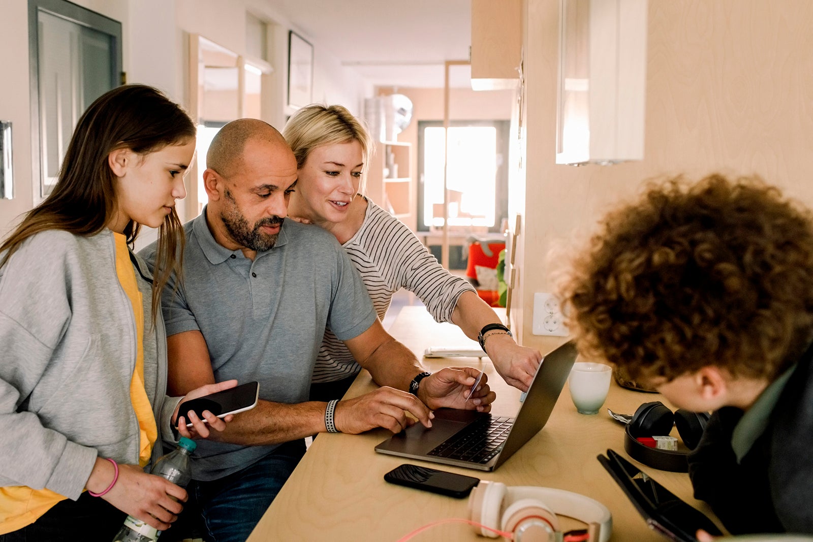 Woman discussing with man over laptop by daughter at kitchen island