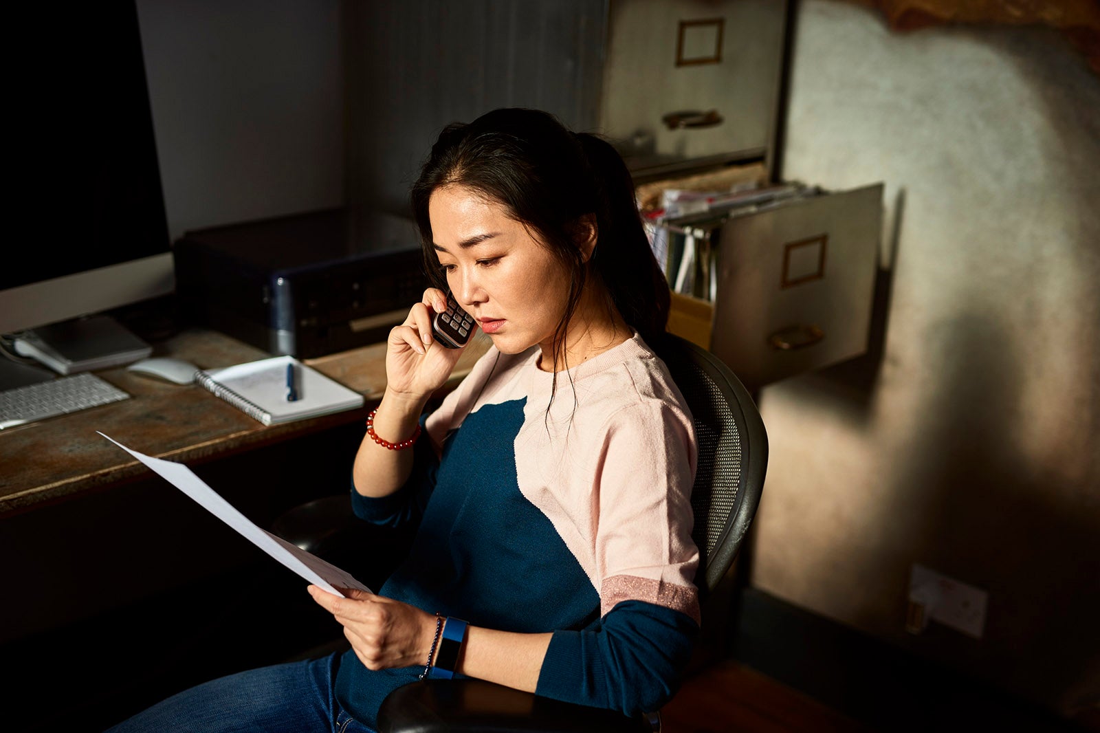 Portrait of Korean woman on cell phone reading important document