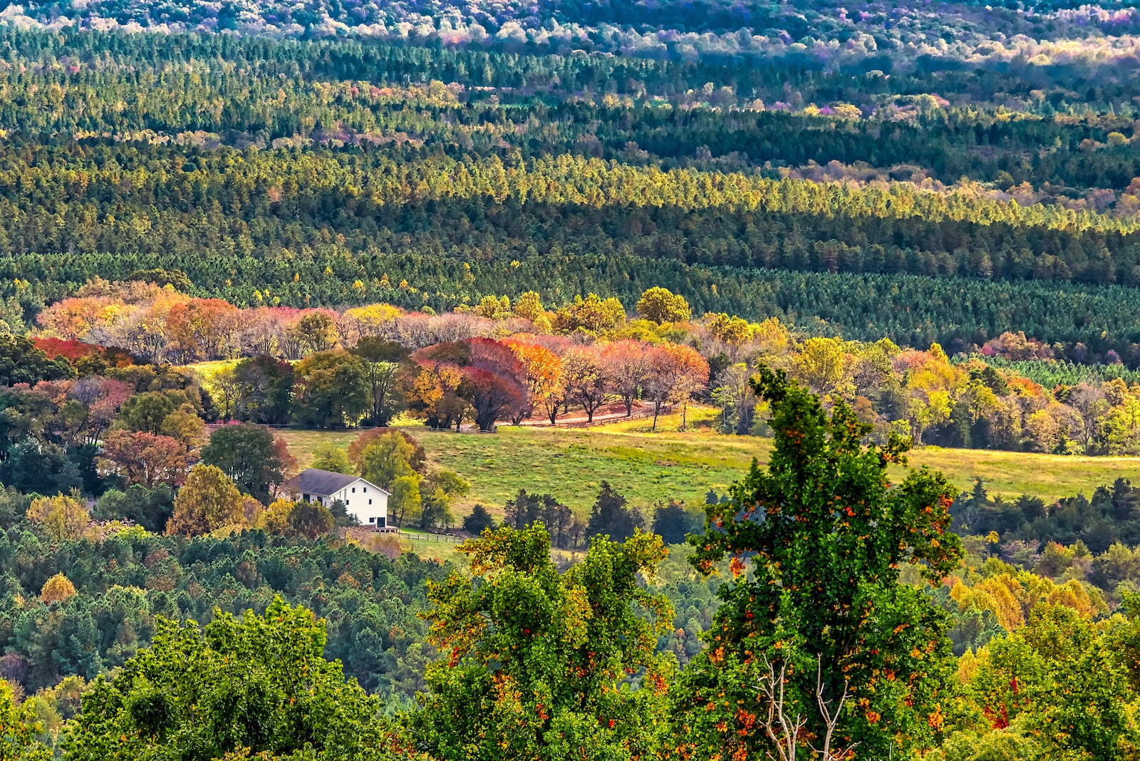 a white farmhouse surrounded by hills and colorful trees