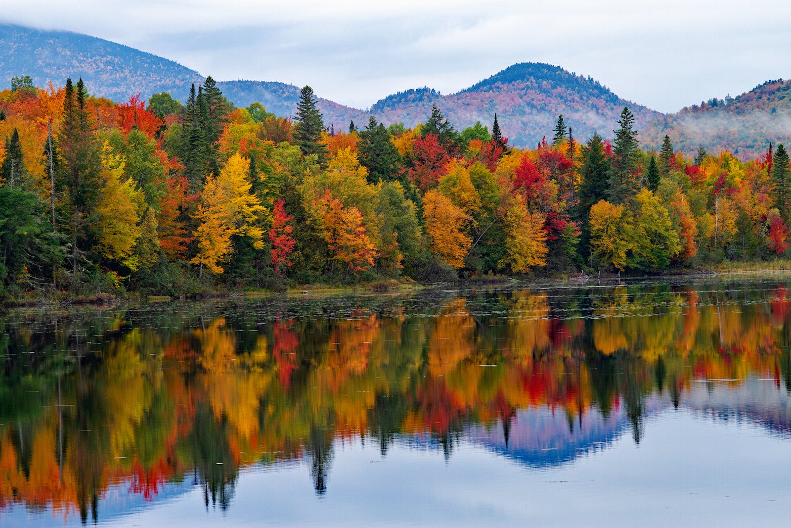 red, yellow, orange and green trees reflected in a lake