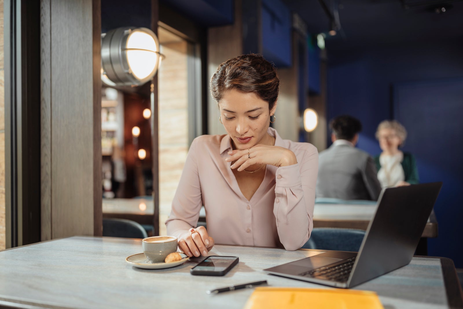 A businesswoman working on her phone and laptop at a hotel