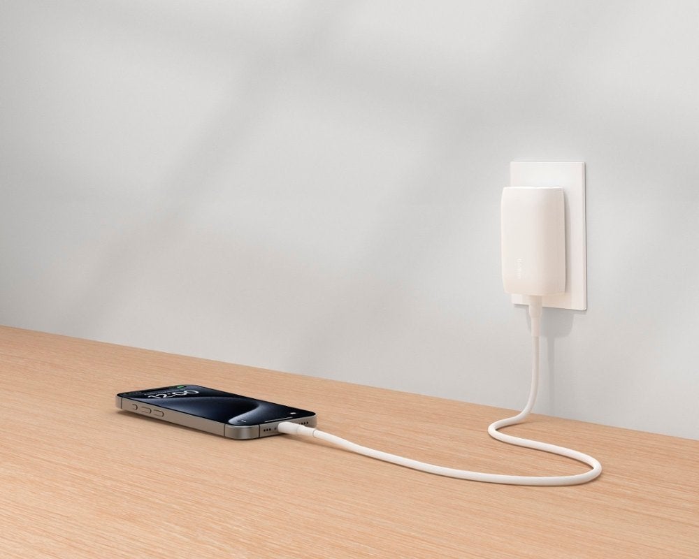 Belkin wall charger plugged into a wall and charging a phone